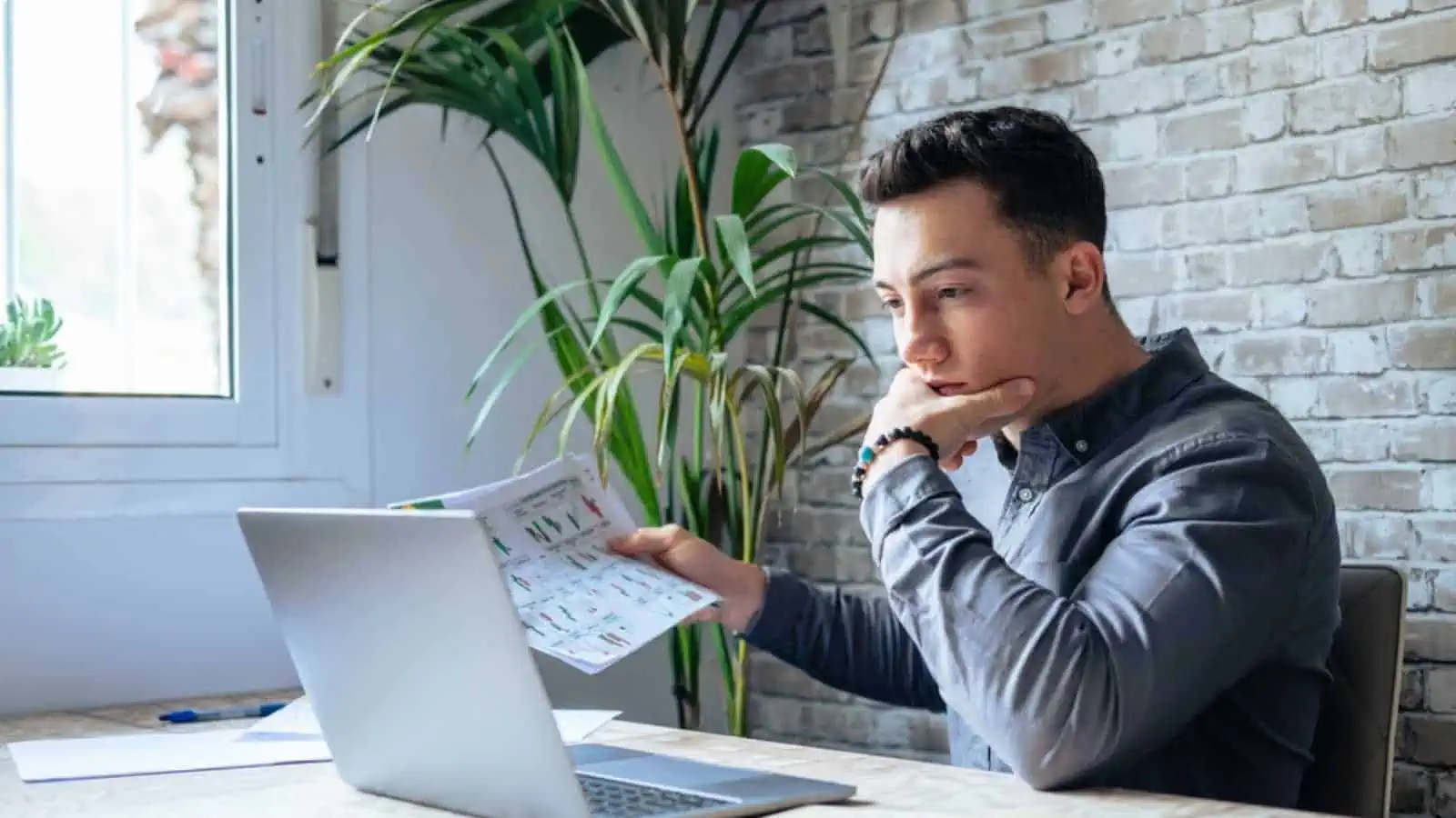 Caucasian business man trader investor analyst looking at financial stock market charts rate dynamic, trading data indexes growth using mobile phone and laptop for cryptocurrency digital analytics.