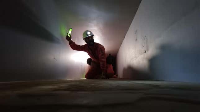 A man wearing a helmet holds a glow stick in a tunnel