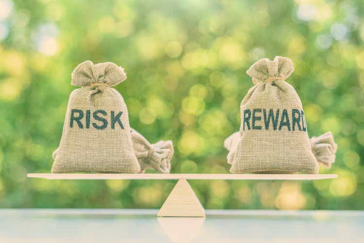 Risk reward ratio / risk management concept : Risk and reward bags on a basic balance scale in equal position, depicts investors use a risk reward ratio to compare the expected return of an investment