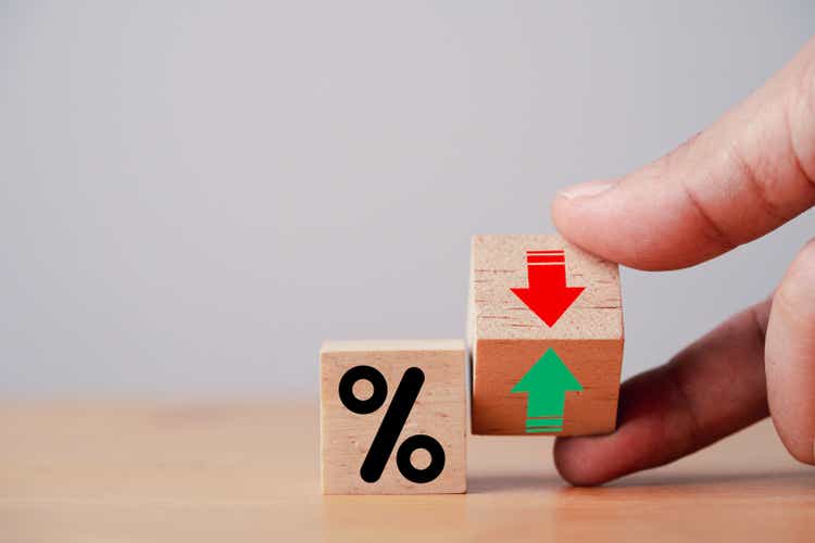 Hand flipping wooden cube block to change between up and down with percentage sign symbol for increase and decrease financial interest rate and business investment growth from dividend concept.