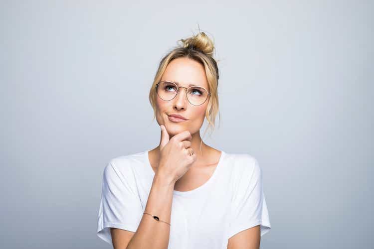 Thoughtful woman with hand on chin looking up