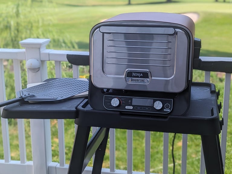 ninja outdoor oven on a table with a golf course behind it