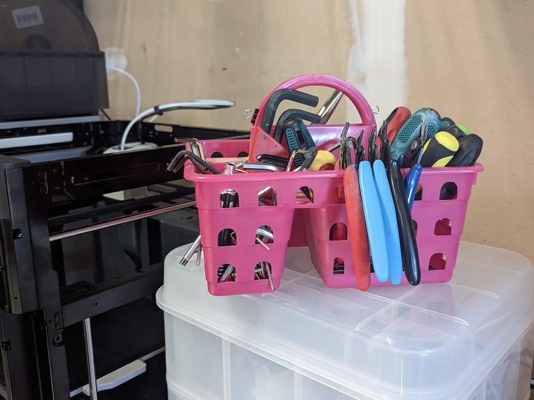 A pink hand basket full of tools