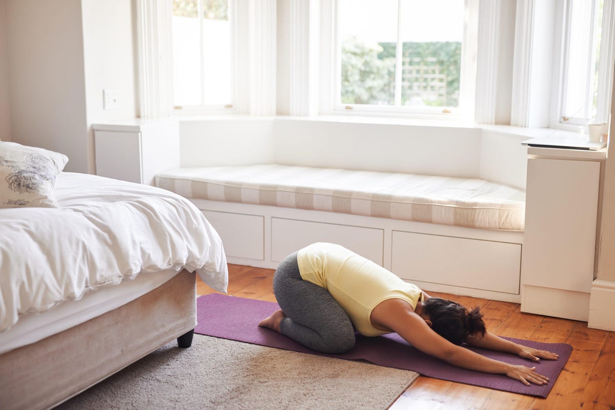 Woman in child's pose on bedroom floor