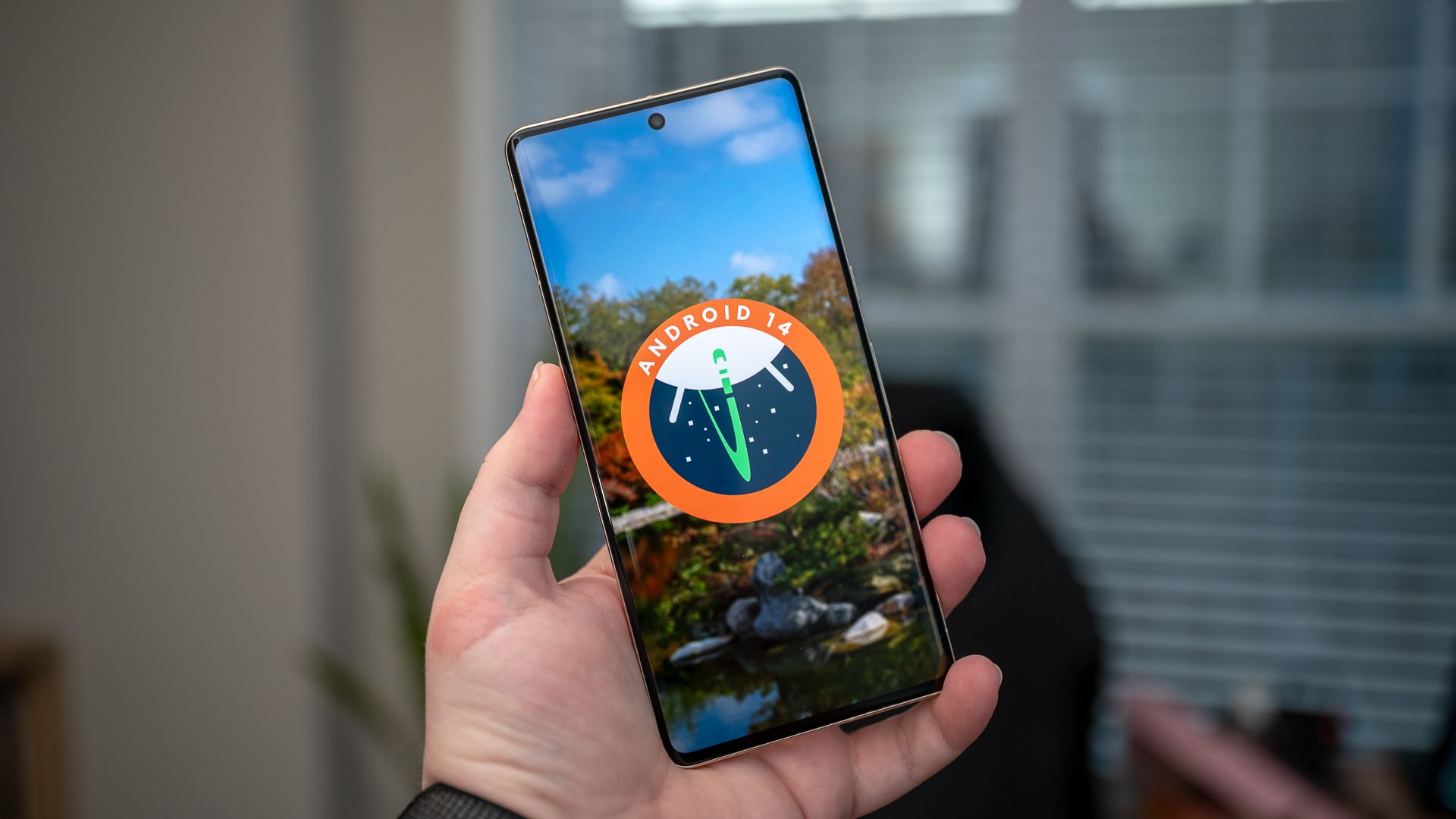 Man holding a phone with the Android 14 logo on its screen. 