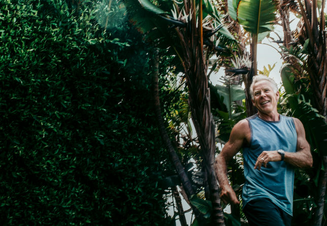 Mark smiles mid-stride in front of a grove of trees.