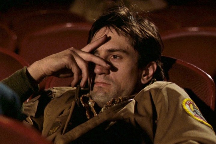 Robert De Niro sits in a movie theater in Taxi Driver.