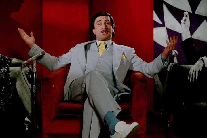 Robert De Niro sits in a red chair in The King of Comedy.