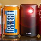 The Anker Nebula Capsule projector beside three soft drink cans