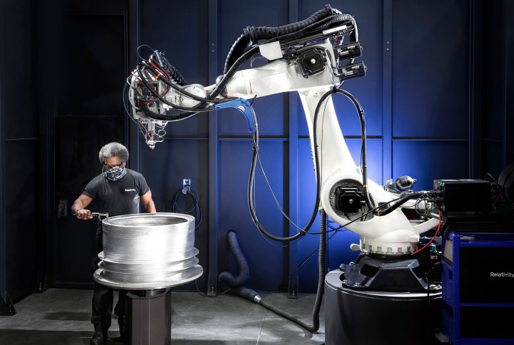 An engineer tests the thickness of a Relativity space rocket 3D print.