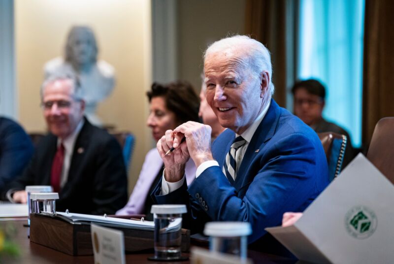 President smiles while sitting at a table during a meeting.