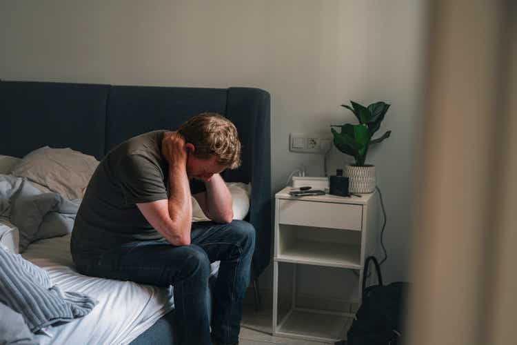 Mature male sitting on his bed - negative emotion