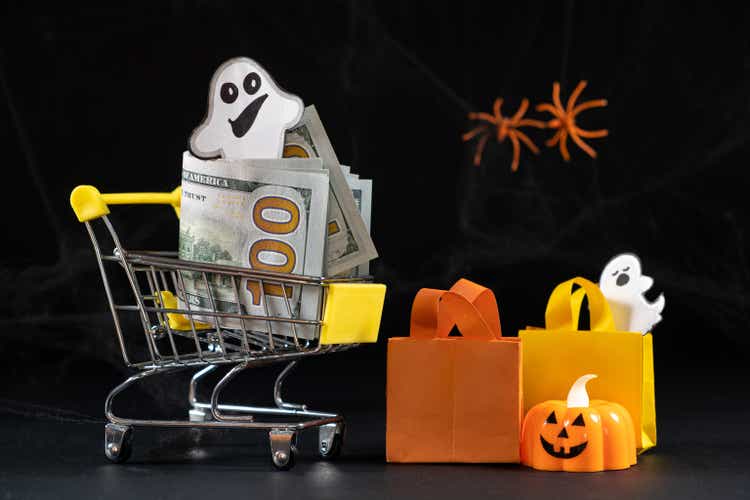 Cart with money hundred-dollar bills, paper bags for purchases. Halloween Sale