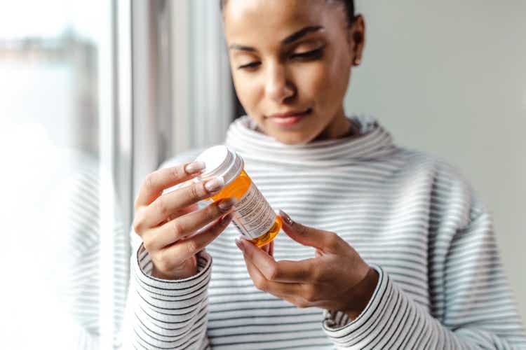 A serious young woman holding a bottle of medicines