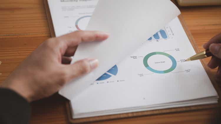 Business man pointing to a pie chart document showing company financial information, He sits in her private office, a document showing company financial information in chart form. Financial concepts