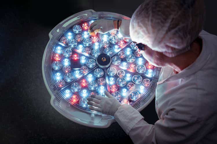 Female engineer preparing operating theatre light in factory clean room