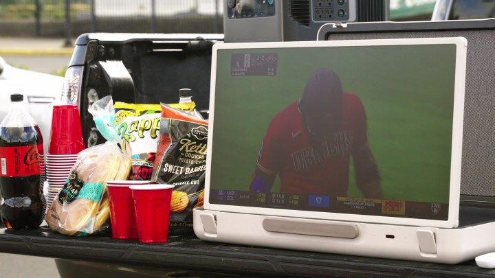 An LG StanbyMe Go briefcase TV showing a baseball game during tailgating. 