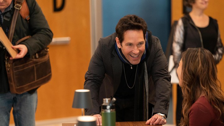 Paul Rudd leaning over a desk smiling in a scene from Only Murders in the Building season 3.