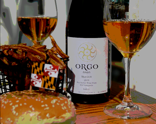 glass of orange wine next to bottle on table