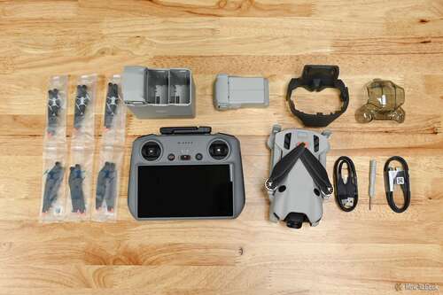 The DJI Mini 4 Pro Fly More Combo Plus (DJI RC 2) components without the storage bag laid out on a wood tabletop