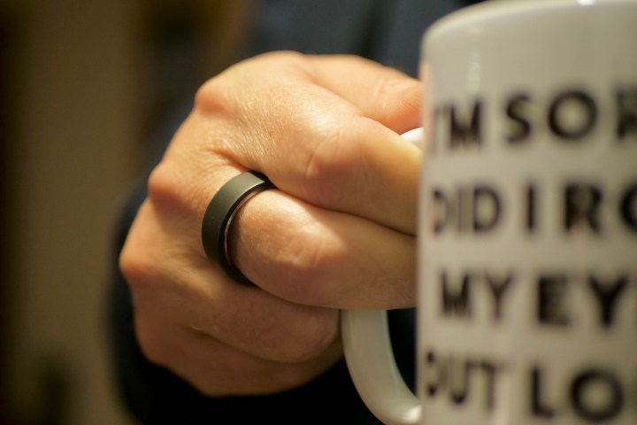 A person wearing the Ultrahuman Ring Air, and holding a mug.