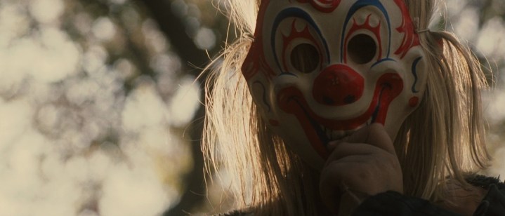 Young Michael Myers pulls a clown mask over his face in Rob Zombie's Halloween