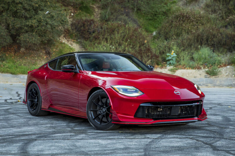 A red Nissan Z Nismo parked by some foliage