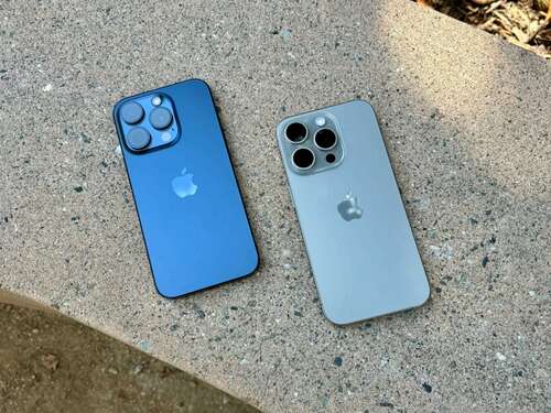 Blue Titanium (left) and Natural Titanium iPhone 15 Pros on a concrete bench.