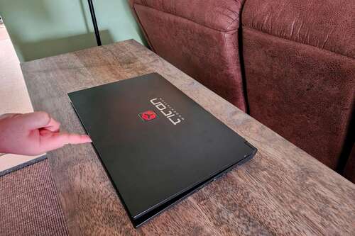 A man lifting a laptop lid with one finger in the middle of the lid.