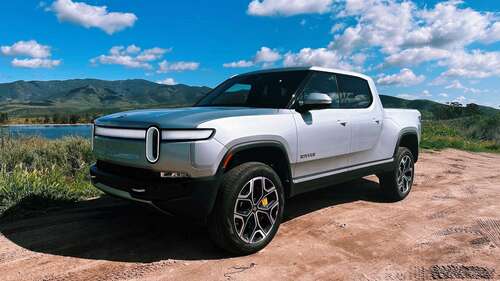 Front end of the Rivian R1T parked by a lake. 