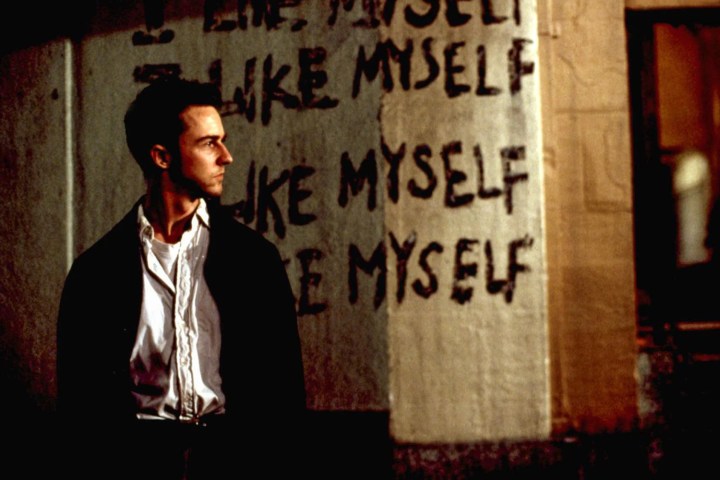 Edward Norton stands near wall graffiti in Fight Club.