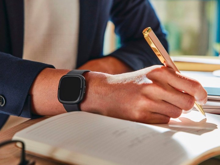 Wearing a Fitbit Sense 2 while working at a desk.