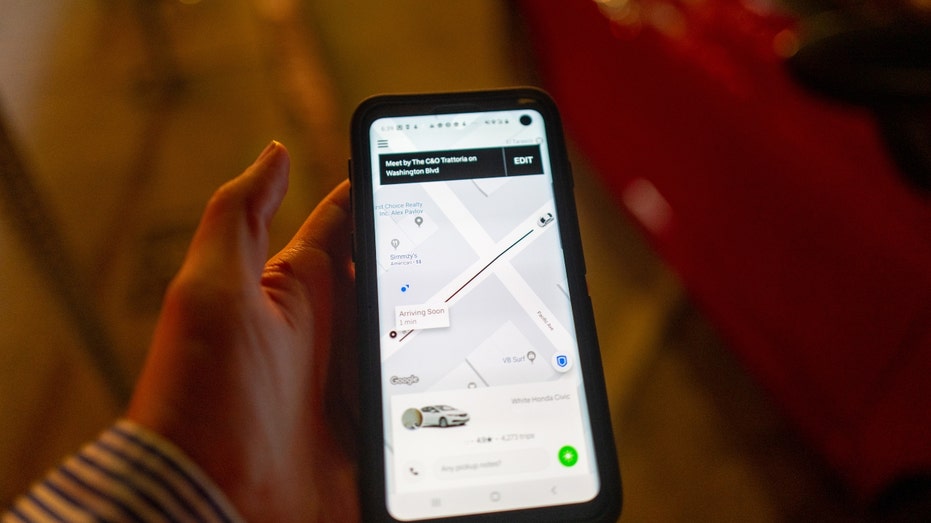 A woman holds up a smartphone showing the Uber app