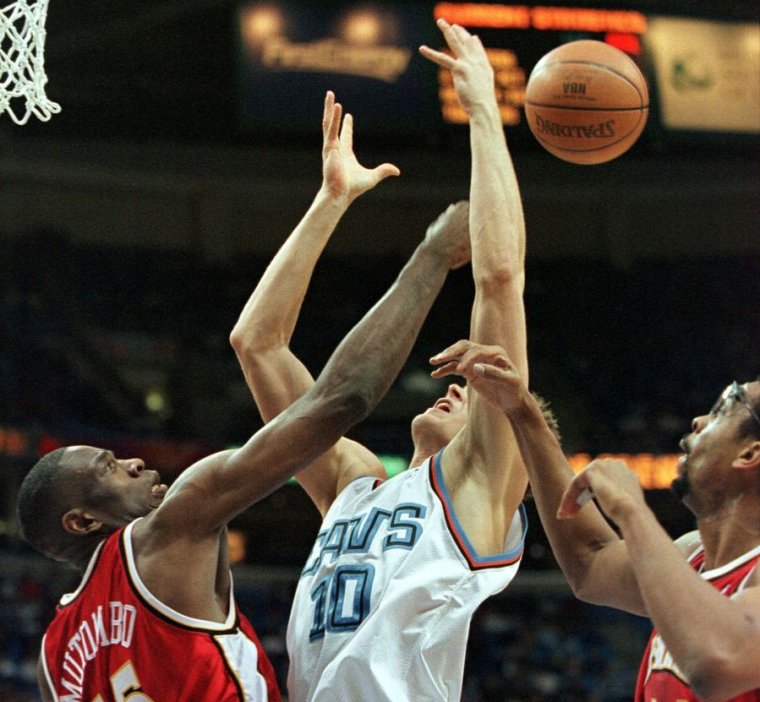 Image of a basketball player having his shot blocked.