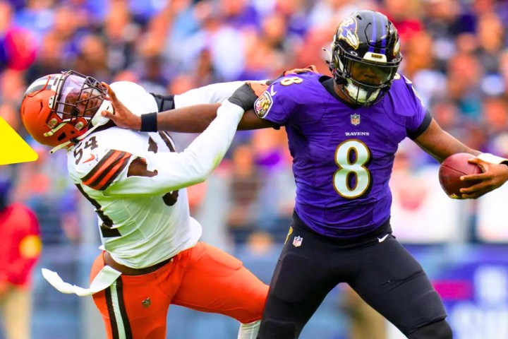 Lamar Jackson stiff arms a defender.