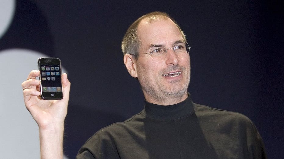 Steve Jobs holding the original iPhone