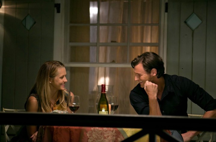 A man and woman sit next to each other at a table.