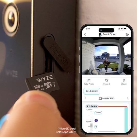 A person holding a microSD card near the Wyze Video Doorbell v2.