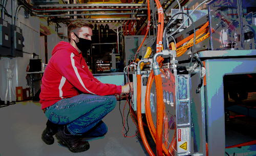 A photo of a man kneeling in front of a machine.  