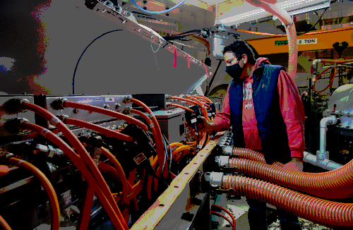 A photo of a man looking at a device with a number of hoses.  