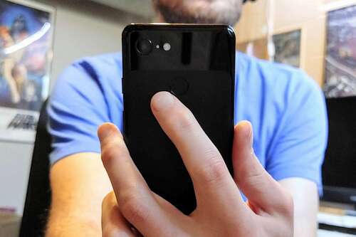 Finger tapping the back of Android phone.