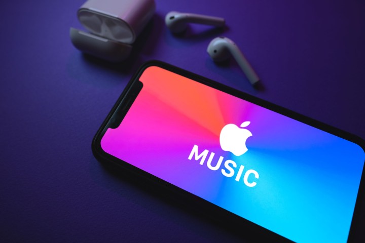 Apple Music screen on an iPhone with a pair of AirPods on a table. 