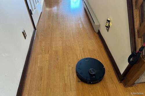 A DreameBot L20 Ultra robot vacuum mopping a hardwood floor.