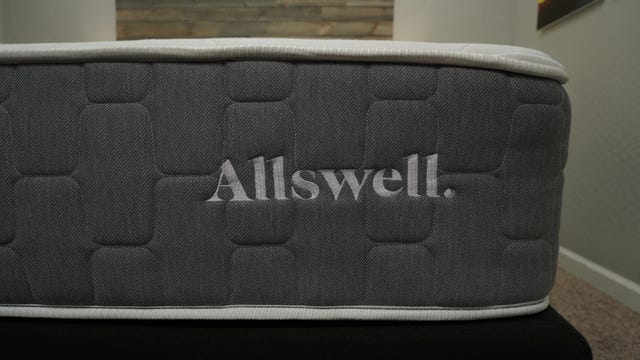 The Allswell Brick Mattress logo sitting on top of a bed frame in a well-lit room