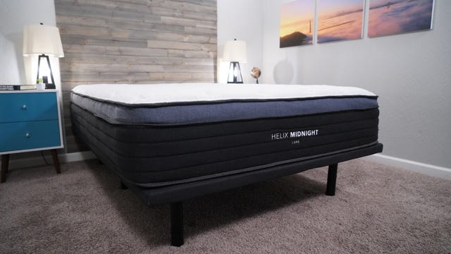 The Helix Midnight Luxe mattress sitting on top of a bed frame in a well-lit room.