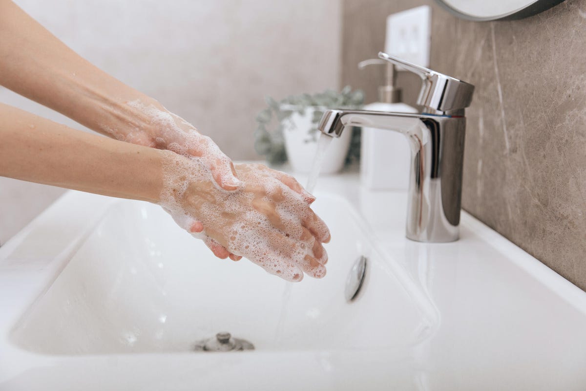 Washing hands under the flowing water tap.