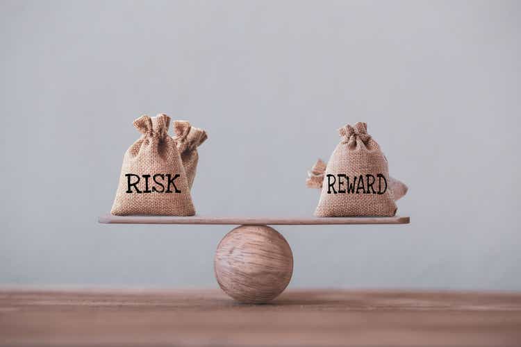 Risk and reward bags on a basic balance scale in equal position on wood table. risk management concept, depicts investors use a risk reward ratio to compare the expected return of an investment