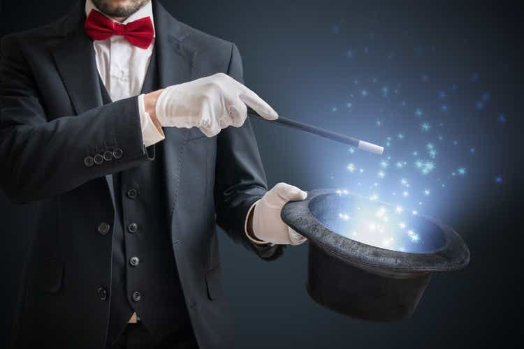 Magician or illusionist is showing magic trick. Blue stage light in background.