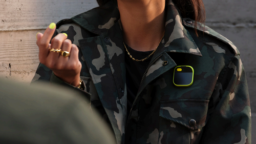 woman wearing a camo jacket with a Human Ai Pin attached