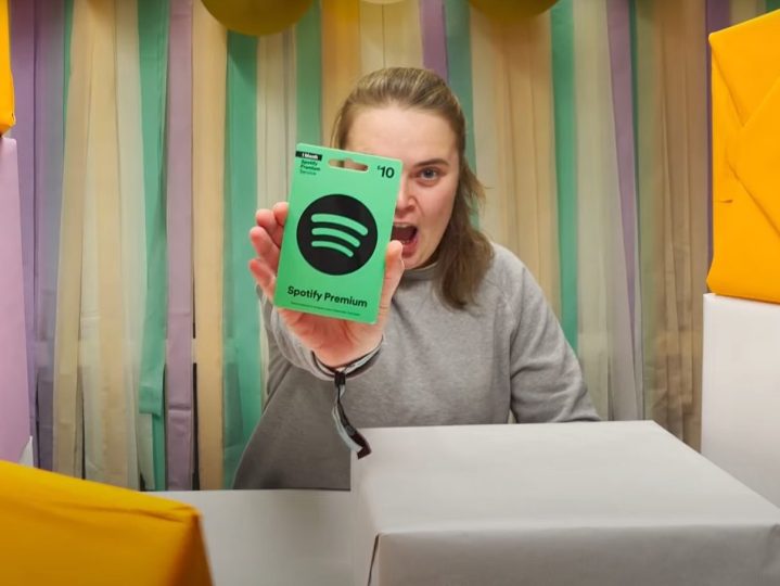 An excited woman holding a Spotify gift card.